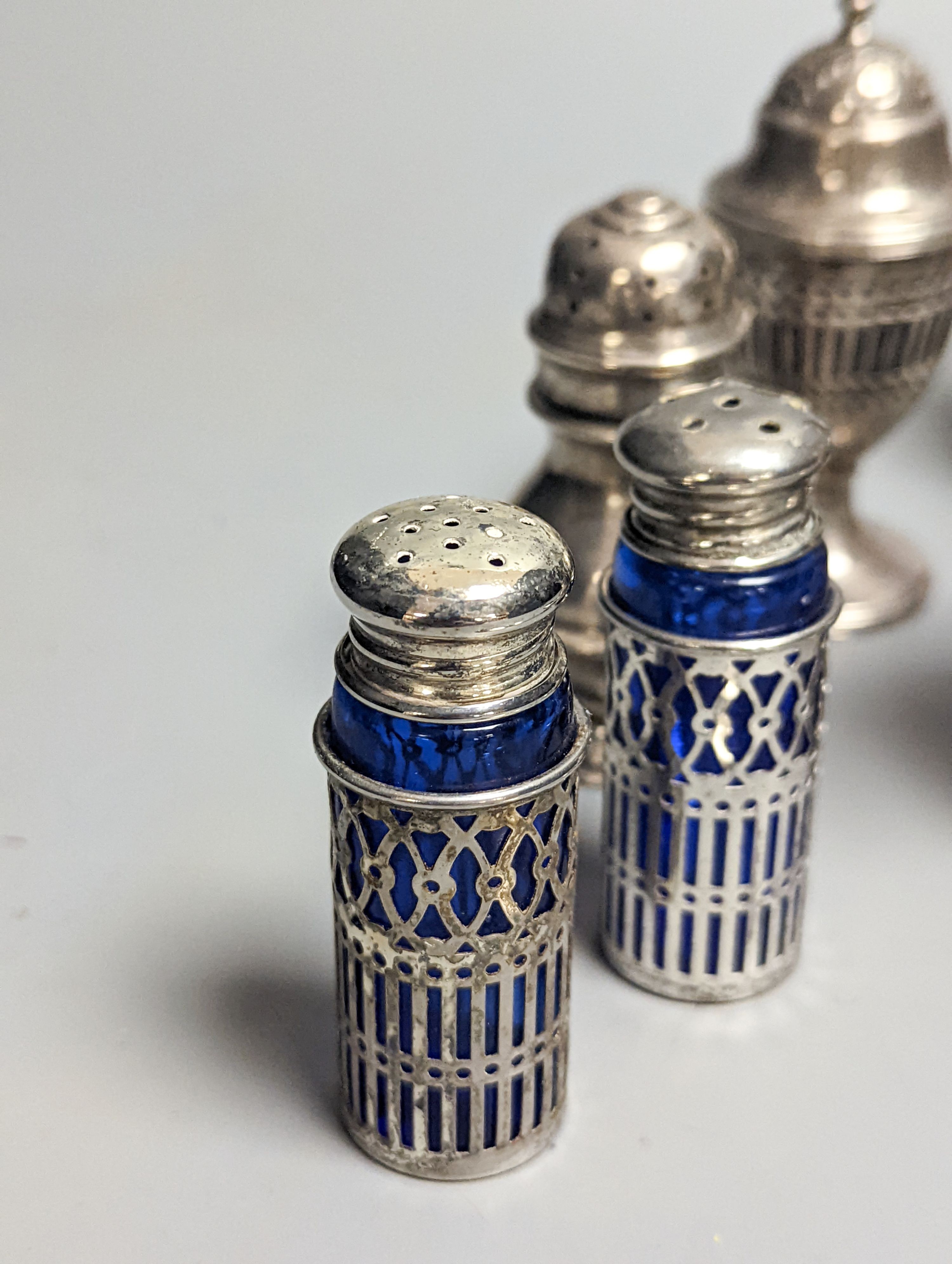 A Victorian embossed silver cream jug, London, 1883, 92mm, two 18th century silver pepperettes, one with plated cover, four later condiments (two silver), a silver spoon and small 800 standard photograph frame.